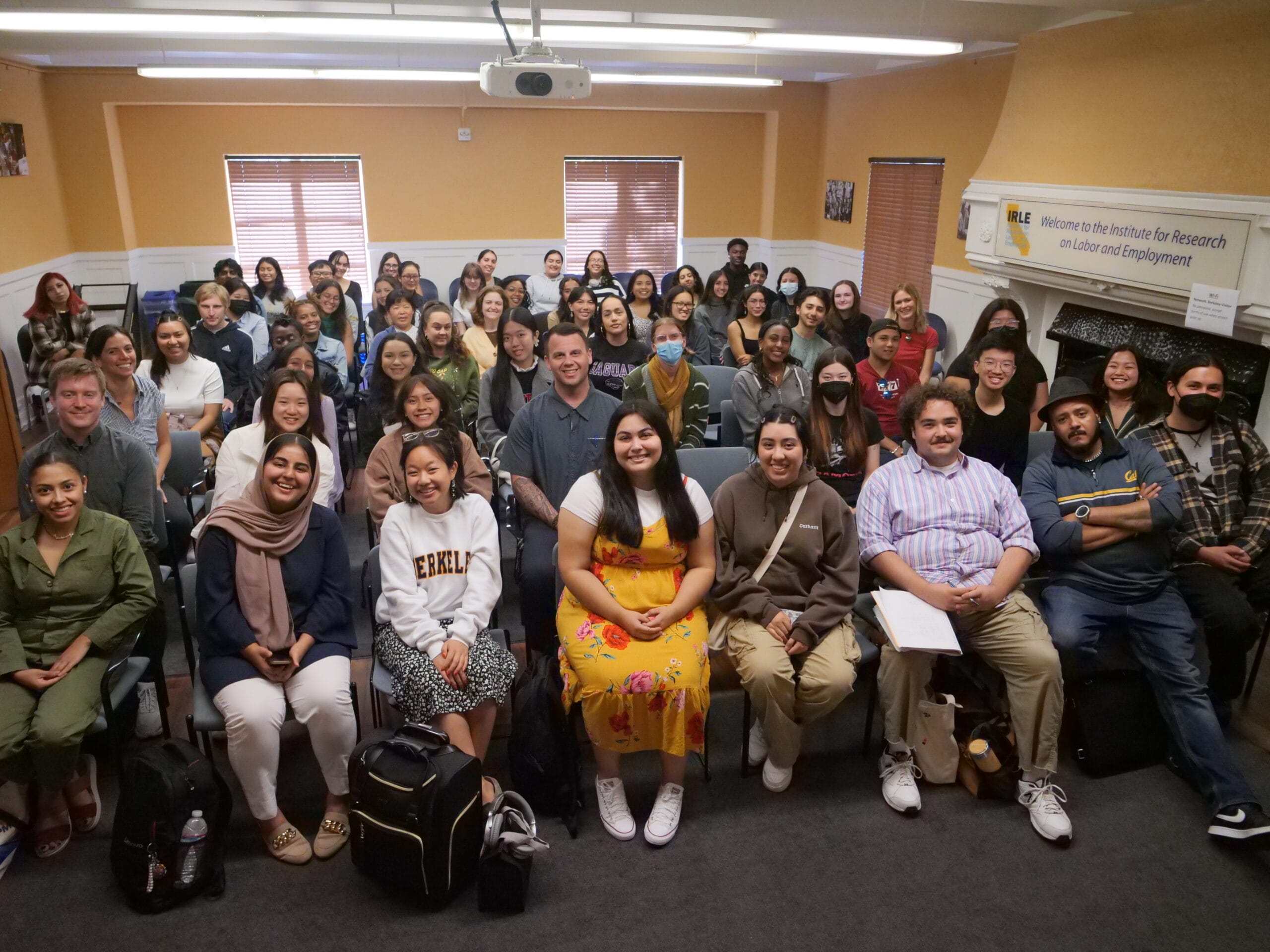 Around 50 smiling undergraduates sit in rows in the IRLE conference room