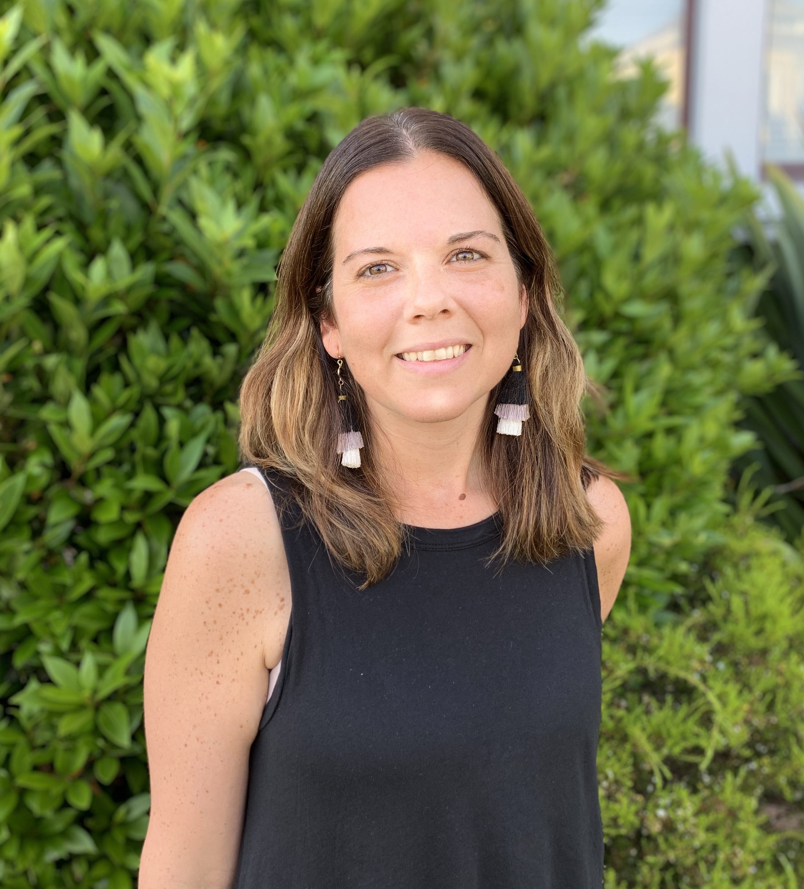 Brenda Sciepura stands smiling against foliage