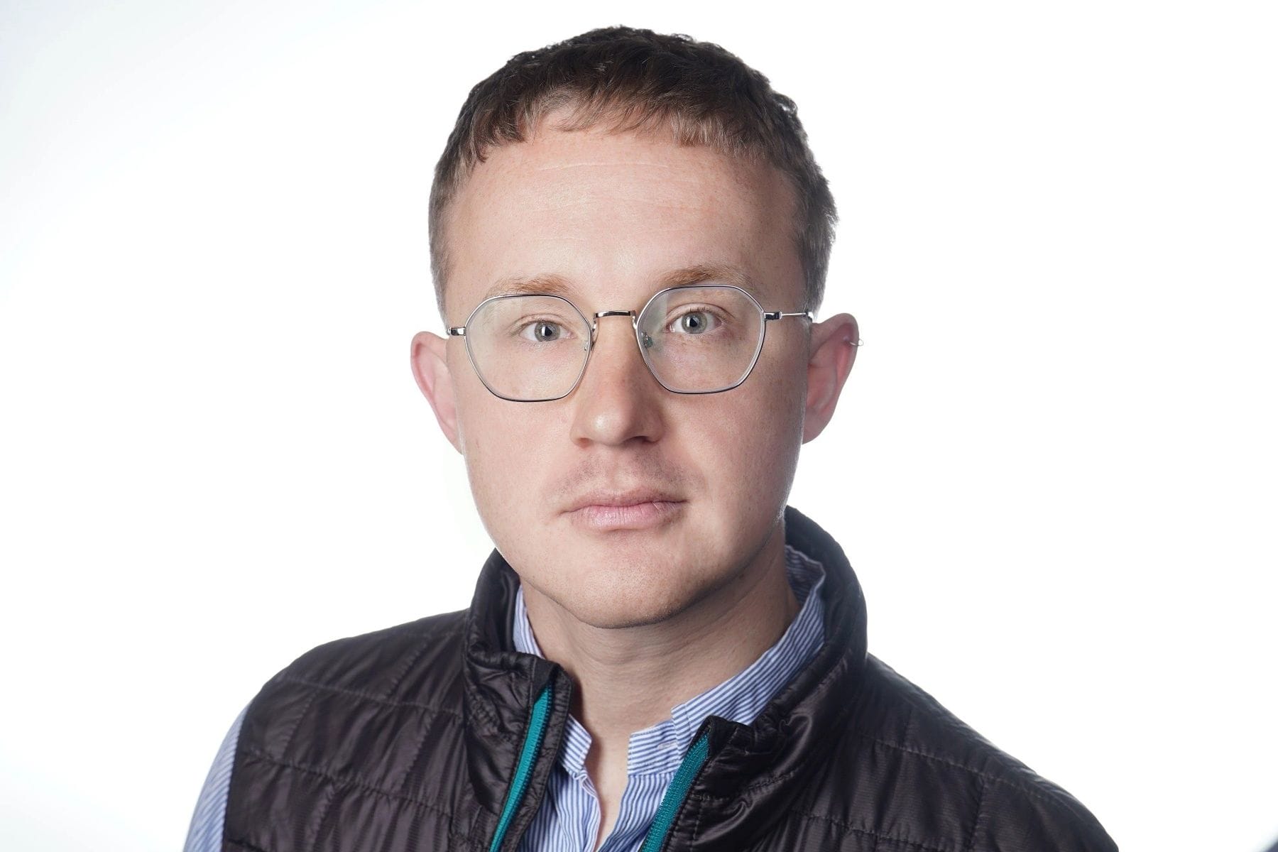 Headshot of Dustin, looking into the camera wearing clear lens glasses with short hair