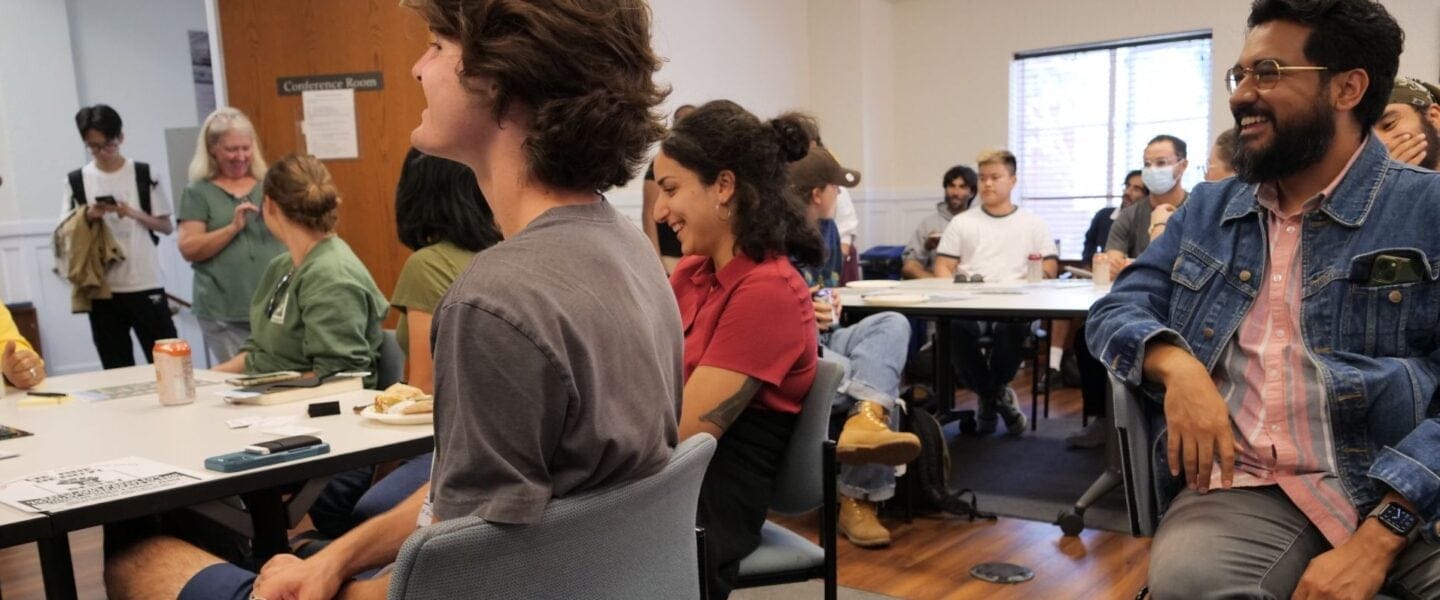 Students and staff sitting and laughing around tables in the IRLE conference room